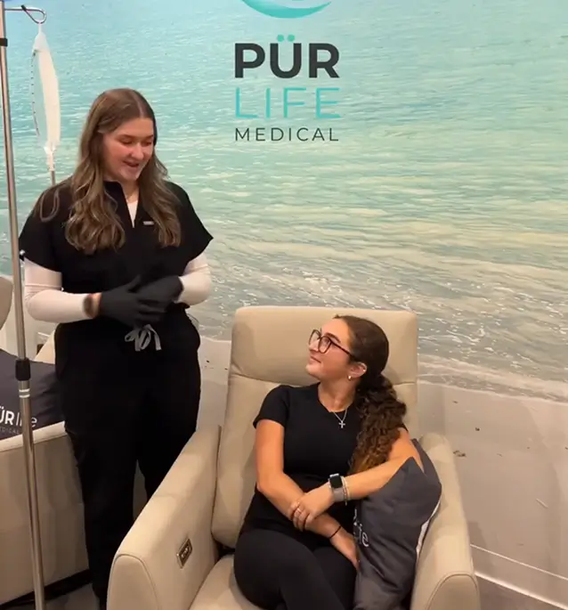 Two women at a PUR Life Medical booth by the water.